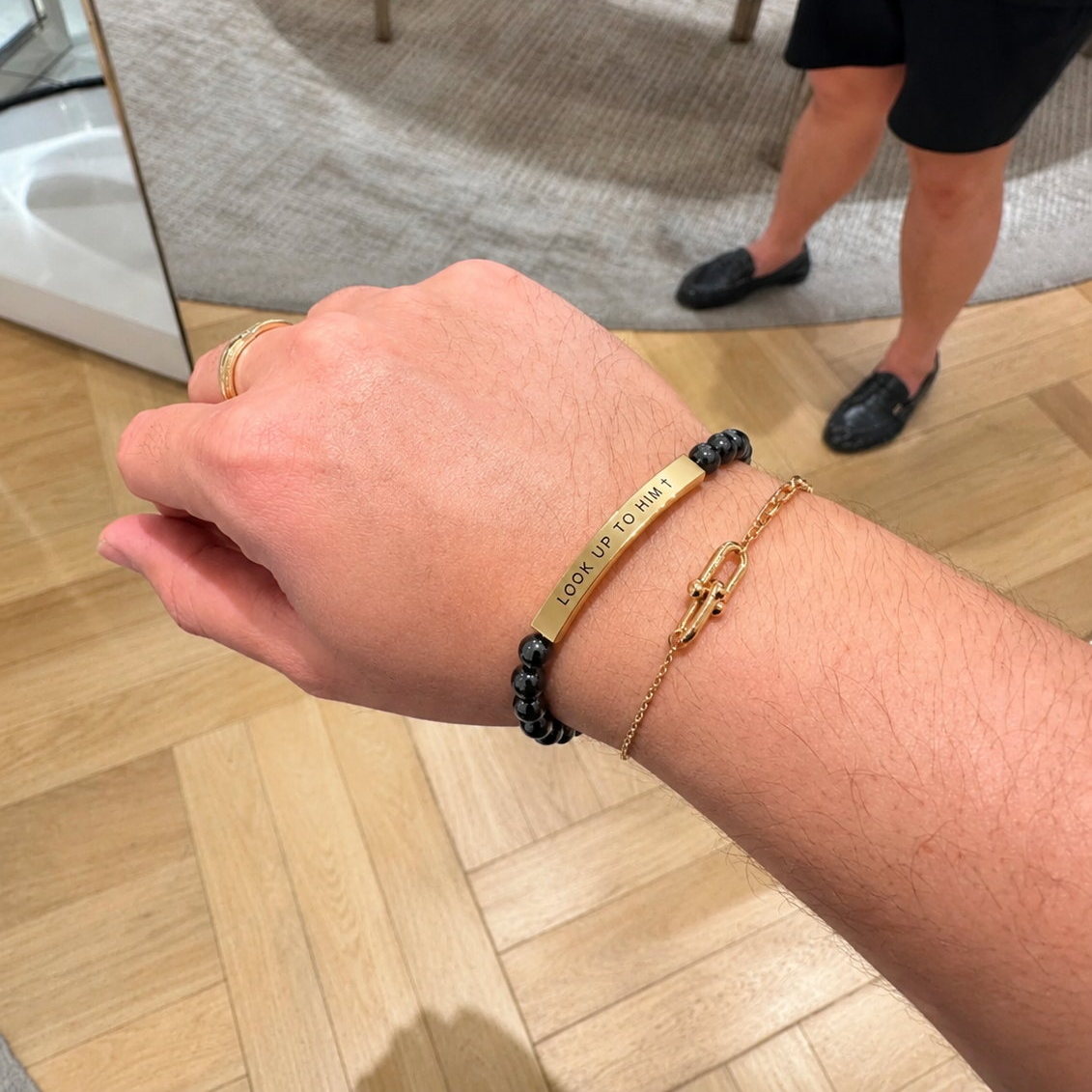 Close-up of a wrist wearing the LOOK UP TO HIM cross bracelet