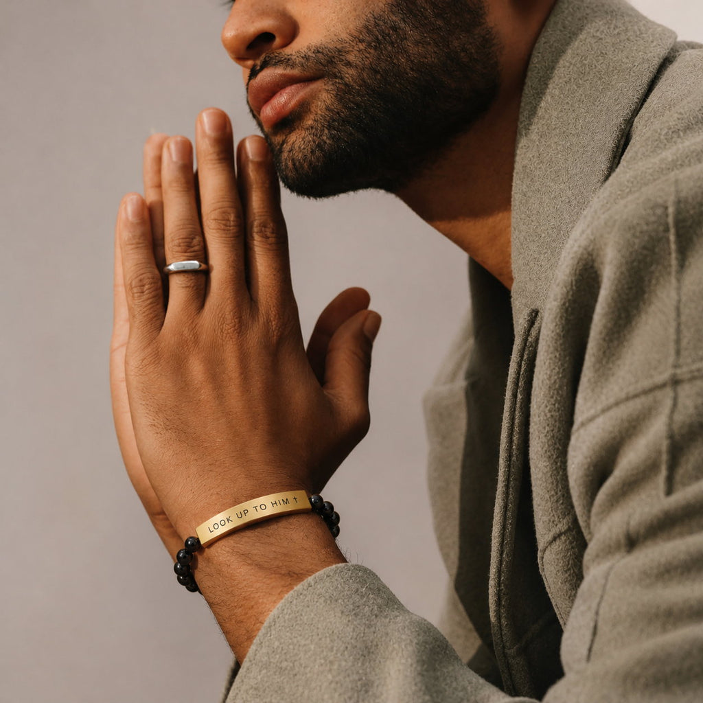 Man with hands folded in prayer wearing the Black & Gold Look Up to Him bracelet
