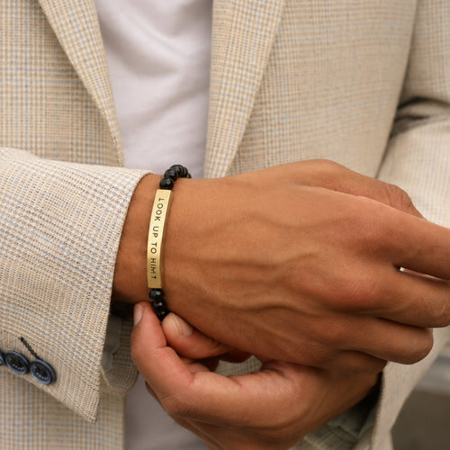 Man in a navy suit wearing the Black & Gold LOOK UP TO HIM bracelet